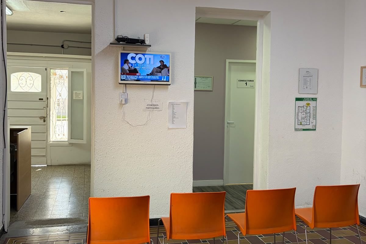 Sala de espera con televisor y acceso al consultorio 1